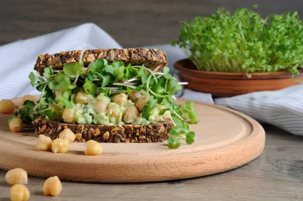 Sandwich of rye bread with cereals with crushed avocado, chickpeas and sprouts of radish shoots.
A great idea for those who watch their health and vegetarian.