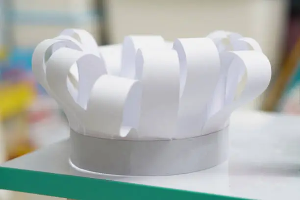 Photo of Chef hat in paper cut art style on white table background