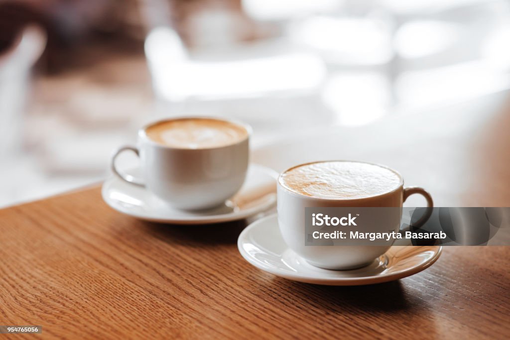 Two cups of cappuccino with latte art Two cups of cappuccino with latte art on wooden desktop Coffee - Drink Stock Photo