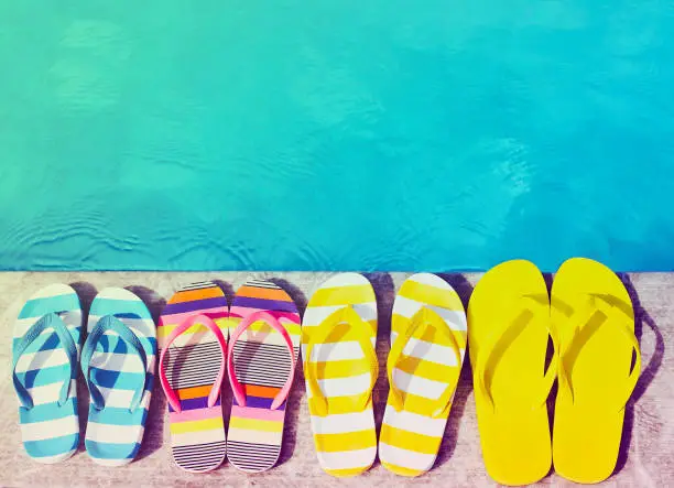 Flip flops on stone background on poolside. Summer family vacation concept