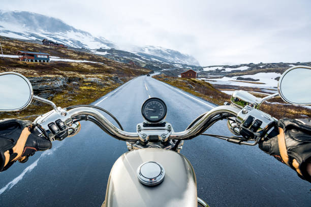 Motorbike/motorcycle speeding down an empty road from over handlebar view. Focus is on the motorbike with road blurred.