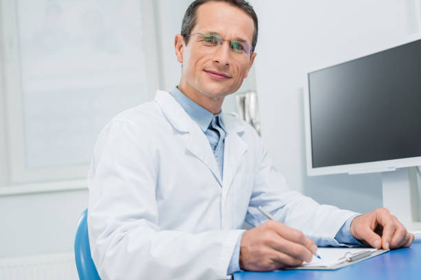istock Doctor filling checklist by computer in modern clinic 954770824
