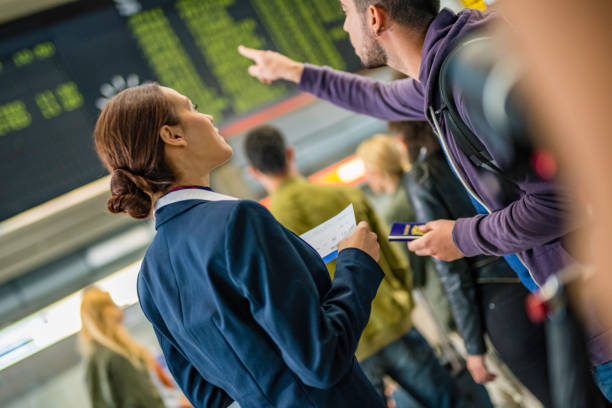 istock Airplane attendant helping traveler at timetables 954779364