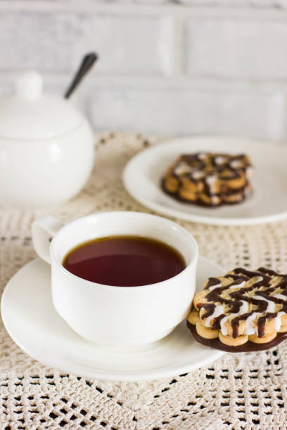 istock Chocolate biscuits on white plate and Cup of tea on the table 954782696