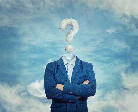 Surreal image as a businessman with invisible face stand with crossed hands and question mark insted of his head, like a mask, for hiding his identity. Interrogation sign symbolizing the head in the clouds, isolated on blue sky background.
