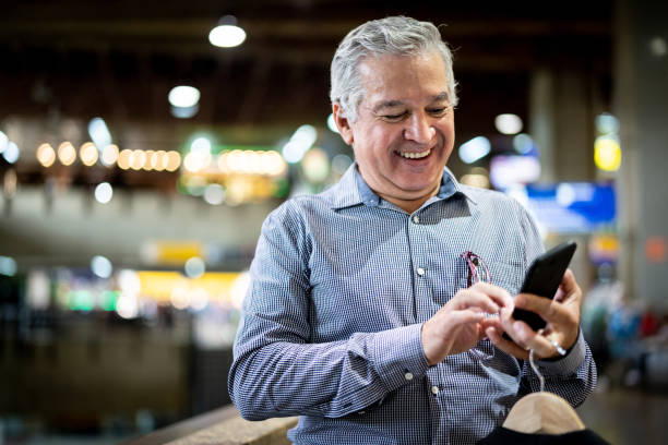 mature businessman using mobile phone at airport - smart phone text messaging mobile phone telephone imagens e fotografias de stock