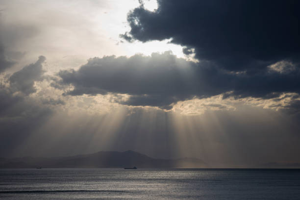 istock gray clouds with sunrays over the sea 954793296