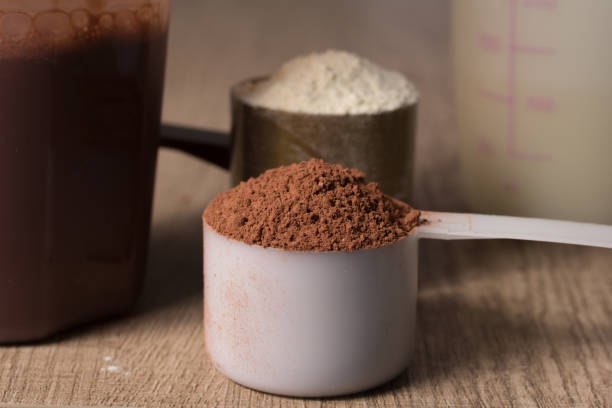 istock Whey Protein. Two scoops with vanilla and chocolate flavour powder, shaker. Wooden table. Close up, texture. 954800102