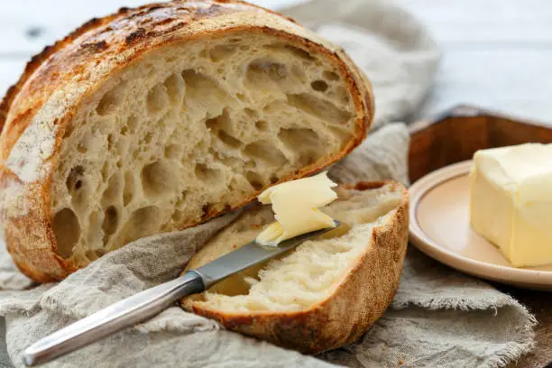 Photo of Hunk of French artisanal bread and a knife with butter.