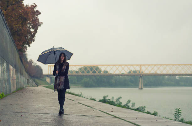 istock Woman with umbrella walking beside river 954813966