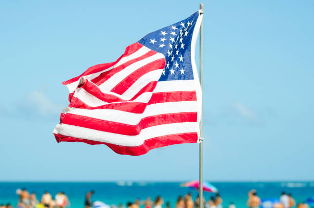 American Flag Flying Over Bright Beach Scene stock photo