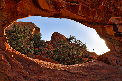 View of backpacker through the Double O Arch. Arches National Park