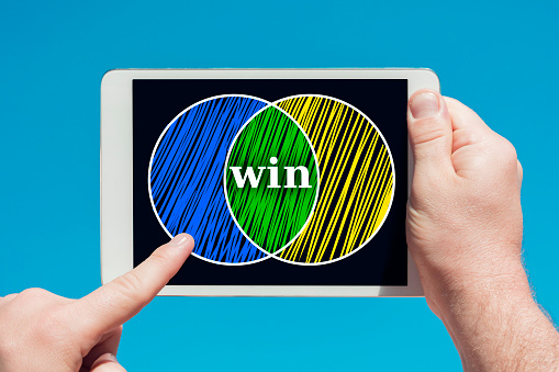 Man holding a tablet device showing a partnership and cooperation symbol in blue sky background.