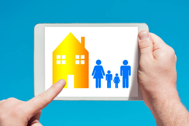 Man holding a tablet device showing family housing concept and touching the screen with a finger with blue sky in background.