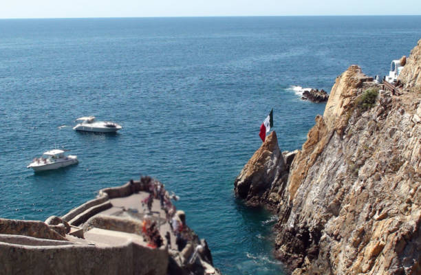 Acapulco, Mexico - May 21, 2011: Pink lights shower the cliffs of La Quebrada cliff diving show while tourists watch on the lower left side while they wait for divers to appear on a late show.