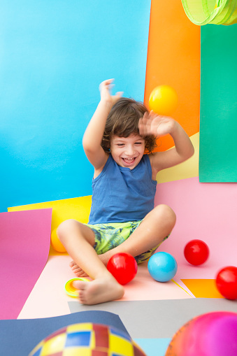 Little happy boy playing with multi colored balls.Cute baby boy playing with balls on colorful background