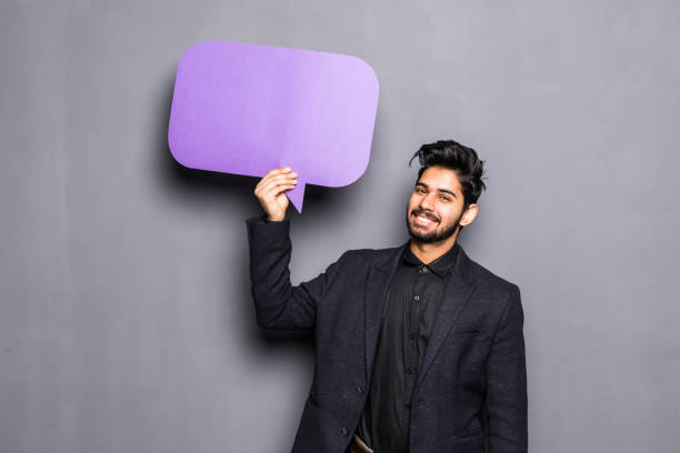 Young indian business man holding a bubble for text, isolated on grey background