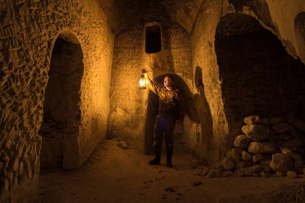 Man explores narrow passage in ancient abandoned underground chalky cave monastery