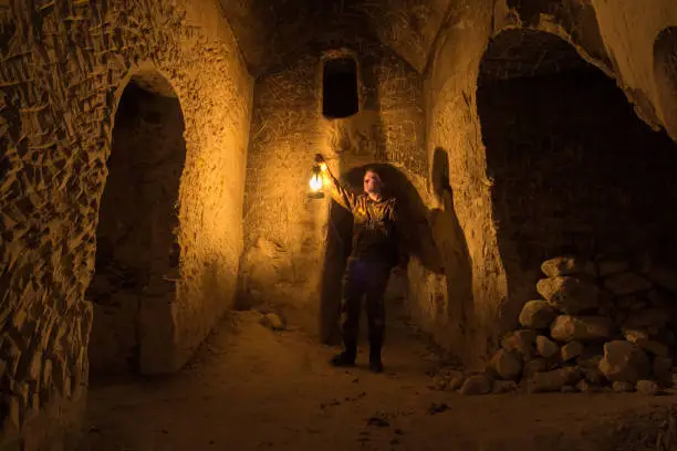 Man explores narrow passage in ancient abandoned underground chalky cave monastery.