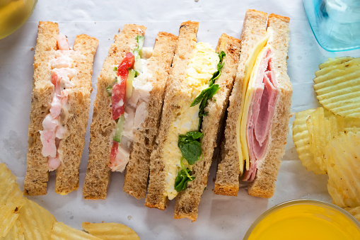 Selection of sandwiches on malted brown bread. Prawns with mayonnaise. Roast chicken breast, vine tomatoes, cucumber, mayonnaise. Egg mayonnaise  and watercress. Ham and cheddar cheese on mayo.