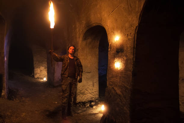 istock Man with torch explores ancient abandoned underground temple 954839356