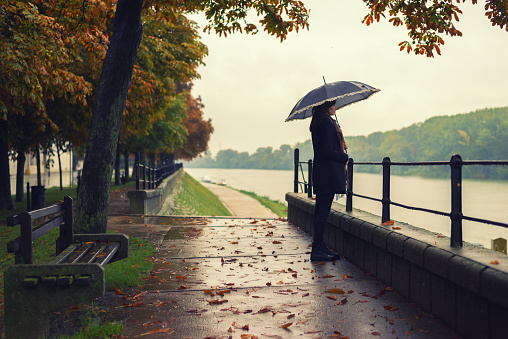 Woman with umbrella standing on the autumn rain.