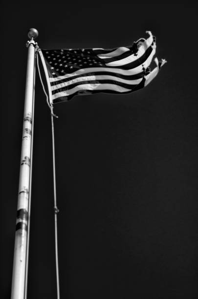 istock Dilapidated American Flag Flying Outdoors in Black and White 954844130