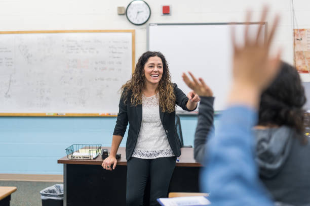 istock Ethnic teacher points to one of her students with a raised hand 954844224