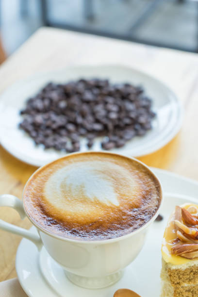 istock Hot coffee late in white cup on blurred raw coffee seed background, 954847986