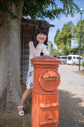 Portrait of young woman with postbox