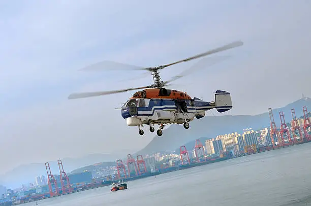 A South Korea Coast Guard helicopter banks to come in for a landing in Busan harbor. The helicopter is a Russian built KA-32C used for heavy lift operations as attested to by the twin rotors.