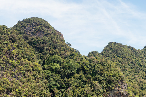 In the Hong Islands rugged Karst mountains are covered with green rainforest vegetation in Thailand, a Southeast Asia travel destination.