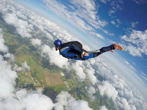 The skydiver plans down to the ground with an open parachute.