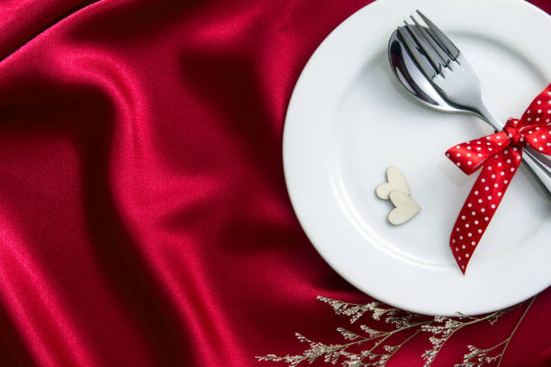 istock red heart shape with White empty plate with fork and spoon on red silk fabric for love dinner concept 954868162