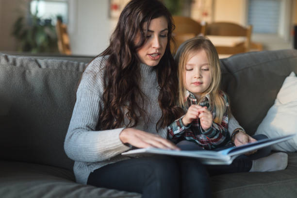 istock Mom reads with her young daughter on the couch 954877000