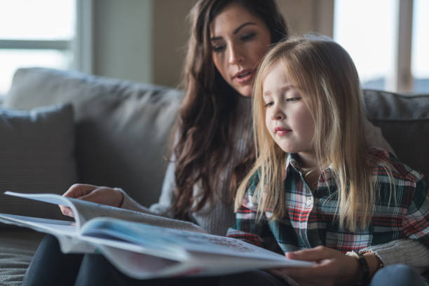 istock Mom reads with her young daughter on the couch 954877010