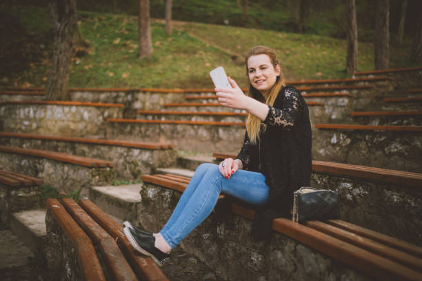 istock Casual dressed woman using phone in the public park 954880610