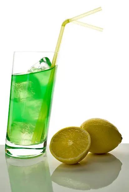 longdrink with tilted liquid surface in slanted glass, two lemons aside
