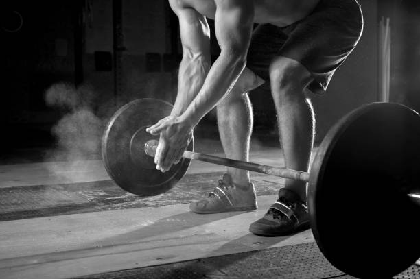 istock Young muscular man exercising with barbell in gym 954895766