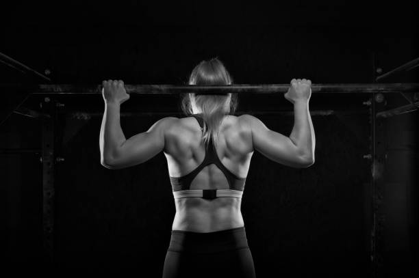 istock Young muscular woman doing pull up exercise in gym 954896144