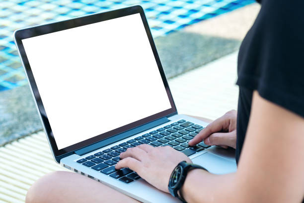 istock Mockup image of a woman using laptop with blank white screen by swimming pool 954896696