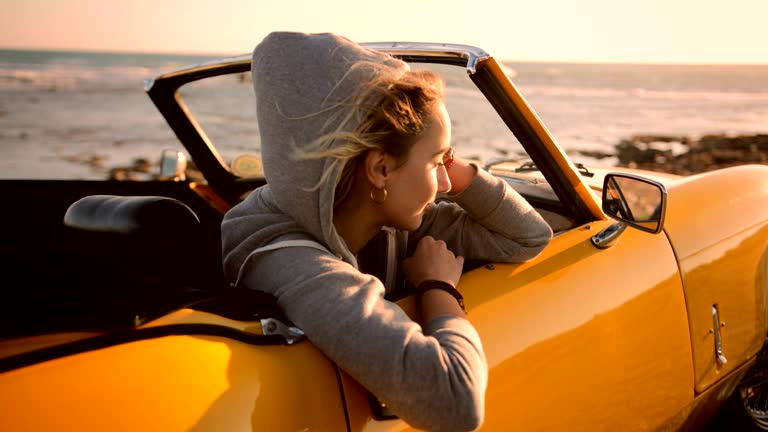 Hipster woman relaxing in convertible car and looking at sunset