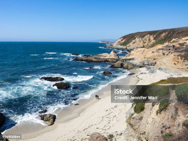 Barefoot Hikers On Beach Below Rocky Cliffs And Waves Along Shore In Bodea Head Marin County California United States Stock Photo - Download Image Now