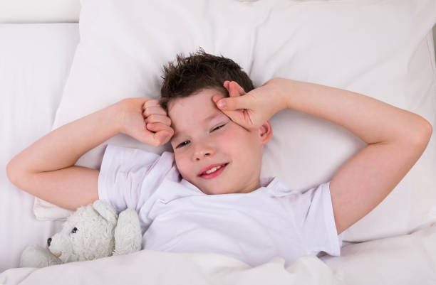 istock boy with a teddy bear woke up in bed 954906126
