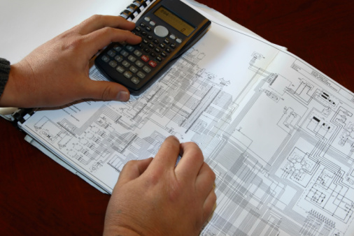 Electronic engineer or student calculating values from a circuit diagram . 