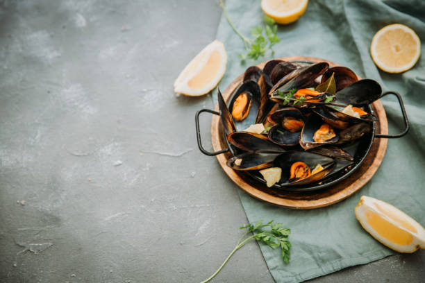 istock Traditional blue mussel in white wine on stone background, top vie, copy space 954919682