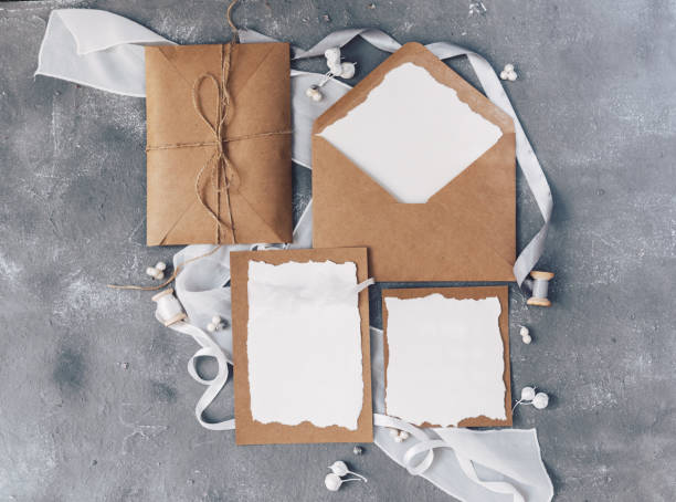 istock Wedding invitation cards template on pastel background. Workspace with paper blank and Kraft envelope. Flat lay, top view 954922494