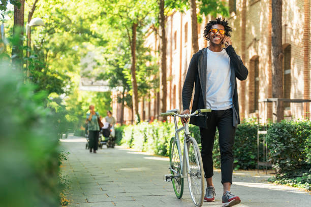 afro junger mann mit handy und fixed-gear fahrrad. - short cycle stock-fotos und bilder