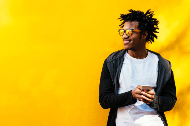 портрет красивого афро-мужчины с помощью своего мобильного телефона. - technology mobile phone clothing smiling стоковые фото и изображения