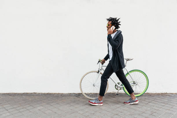 携帯電話と固定ギアの自転車を使用してアフロの若い男。 - short cycle ストックフォトと画像
